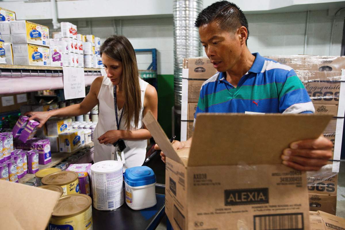 Social worker Danielle Holm, left, and Walter Dong of the Edmonton Food Bank, right, pack care packages for evacuees of the wildfires in and around Fort McMurray at the Edmonton Food Bank in Edmonton Alta, on Wednesday, May 4, 2016.