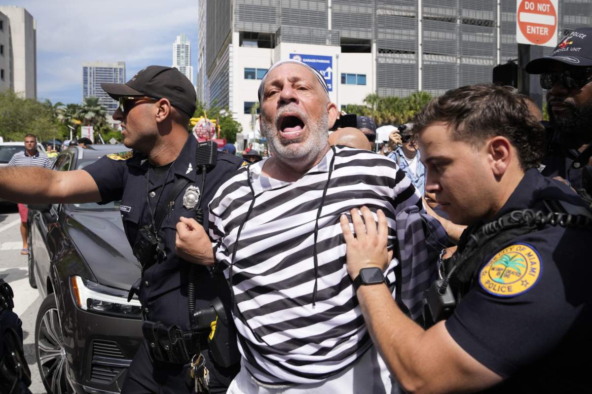 Domenic Santana is detained after jumping in front of the car carrying former President Donald Trump as he left the Wilkie D. Ferguson Jr. U.S. Courthouse, Tuesday, June 13, 2023, in Miami. (AP Photo/Lynne Sladky)