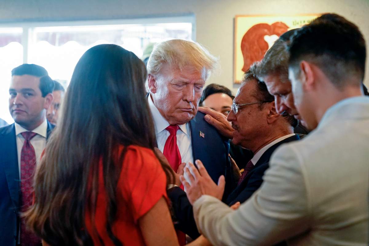 Former President Donald Trump prays with pastor Mario Bramnick, third from right, and others at Versailles restaurant on Tuesday, June 13, 2023, in Miami.
