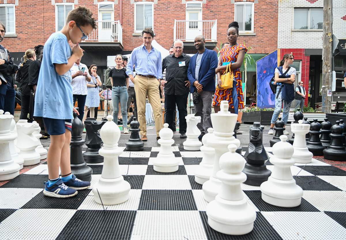 Prime Minister Justin Trudeau, fourth right, looks on as a young boy ponders his next chess move during an event on Saint-Jean-Baptiste in Montreal, Saturday, June 24, 2023.