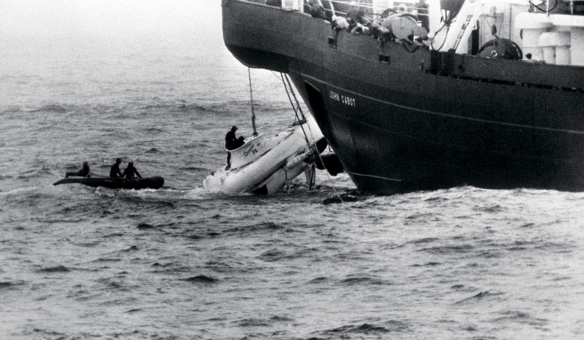 Divers begin to open the hatch of the minature submarine Pisces III as she breaks water under the John Cabot after being hauled from the Atlantic seabed 240 km off the coast of Ireland.