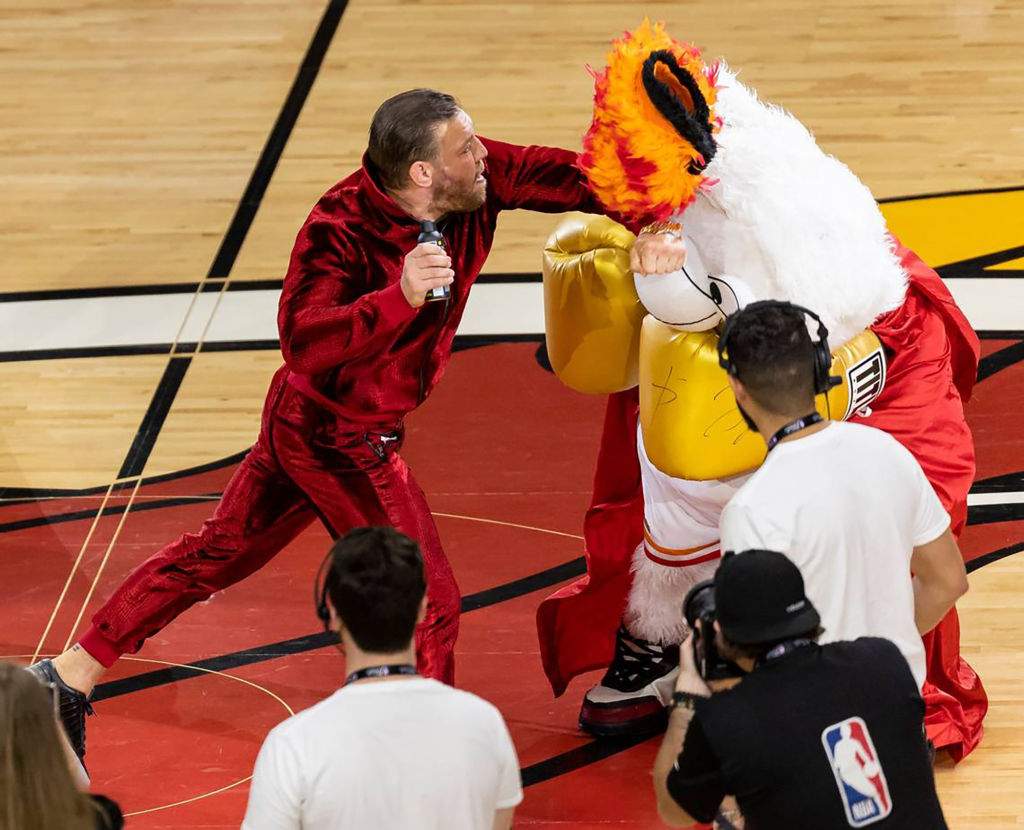 Mixed martial arts fighter Conor McGregor, left, swings at Miami Heat mascot Burnie during a timeout period in Game 4 of the NBA Finals against the Denver Nuggets at the Kaseya Center on June 9, 2023, in Miami.