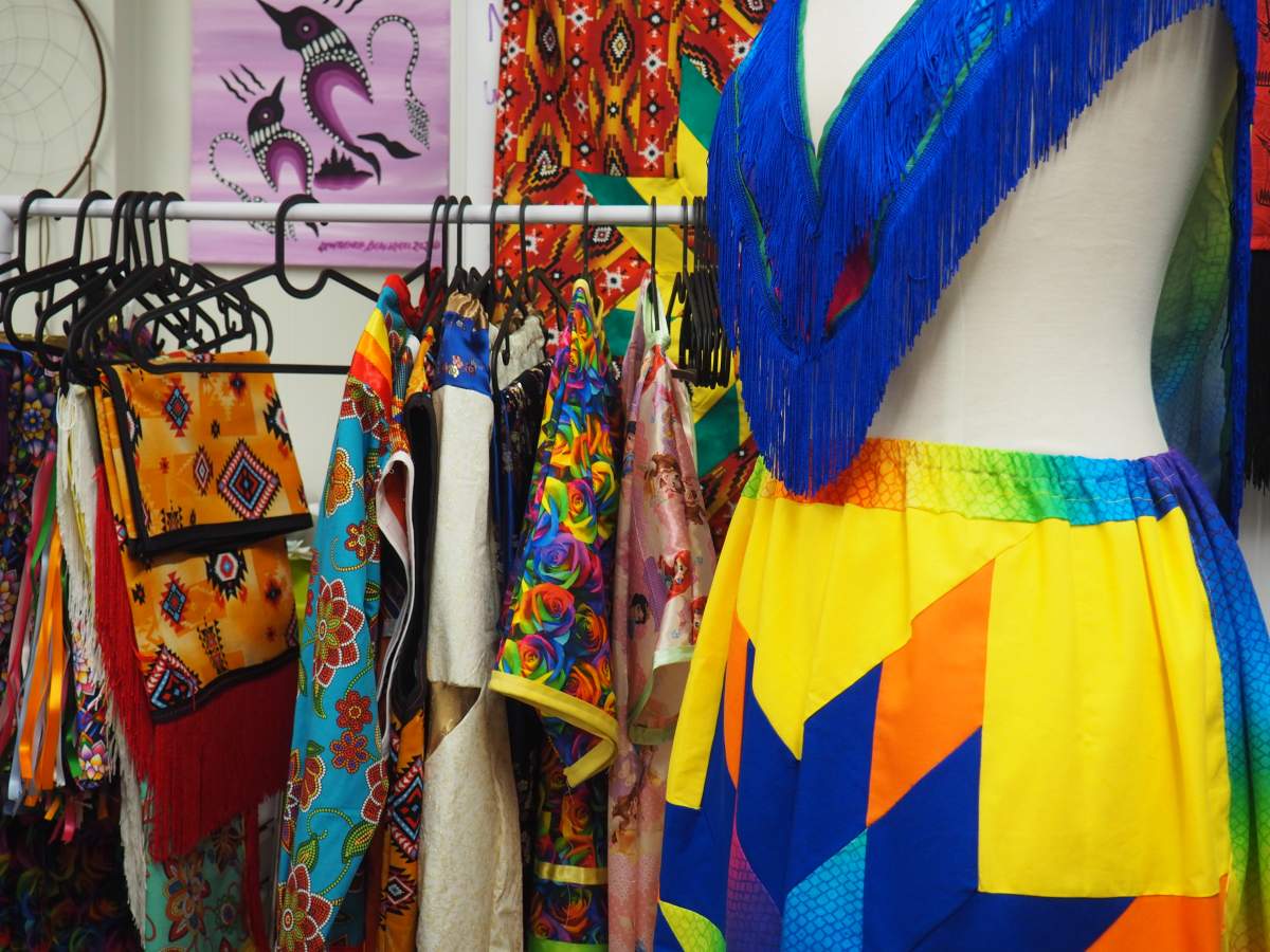 regalia hangs from a garment rack, a mannequin wears a ribbon skirt