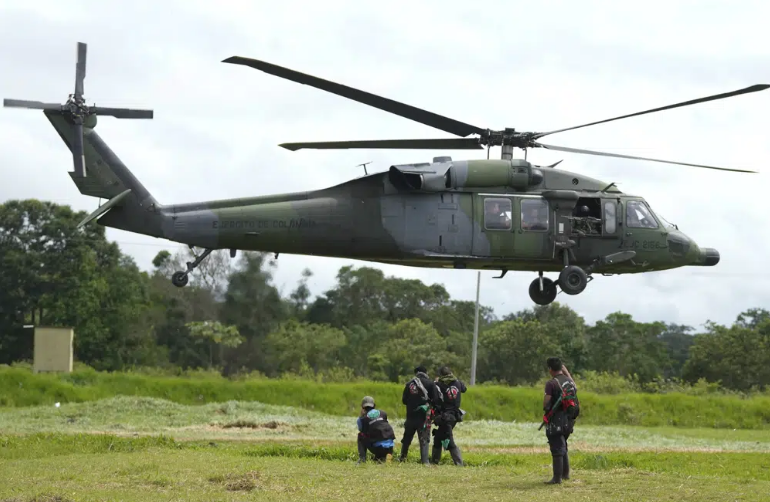 A helicopter taking off. There is a rope hanging.