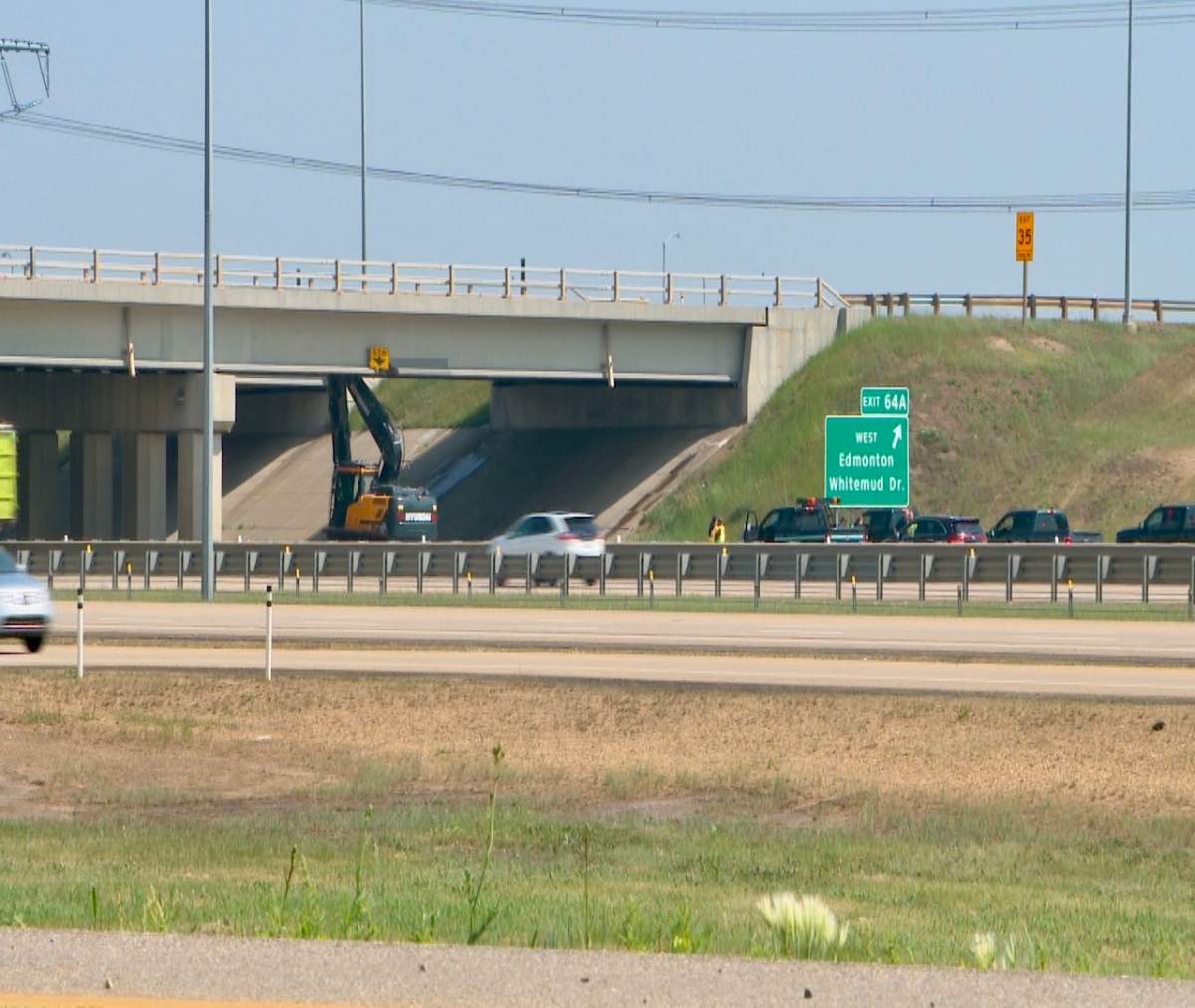 An excavator on a semi trailer collided with overpass bridge deck of Whitemud Drive at Anthony Henday Drive in southeast Edmonton on Friday, June 16, 2023.