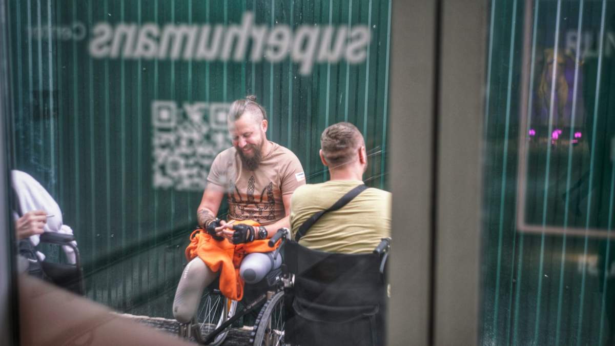 Ukrainian combat veterans with prosthetics laugh while sitting in wheelchairs at a support centre in Lviv.