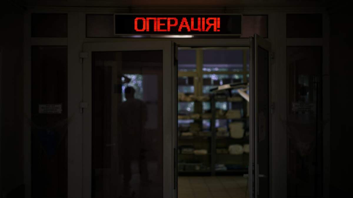 A Ukrainian surgery ward sign lights up in red in a combat hospital near Kyiv.