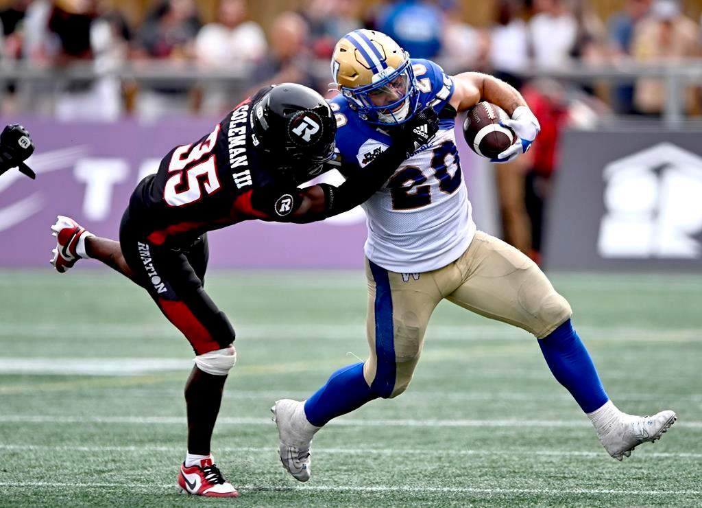 Winnipeg Blue Bombers running back Brady Oliveira (20) tries to evade the tackle of Ottawa Redblacks defensive end Lorenzo Mauldin IV (94) during first-half CFL football action in Ottawa on Saturday, July 15, 2023.