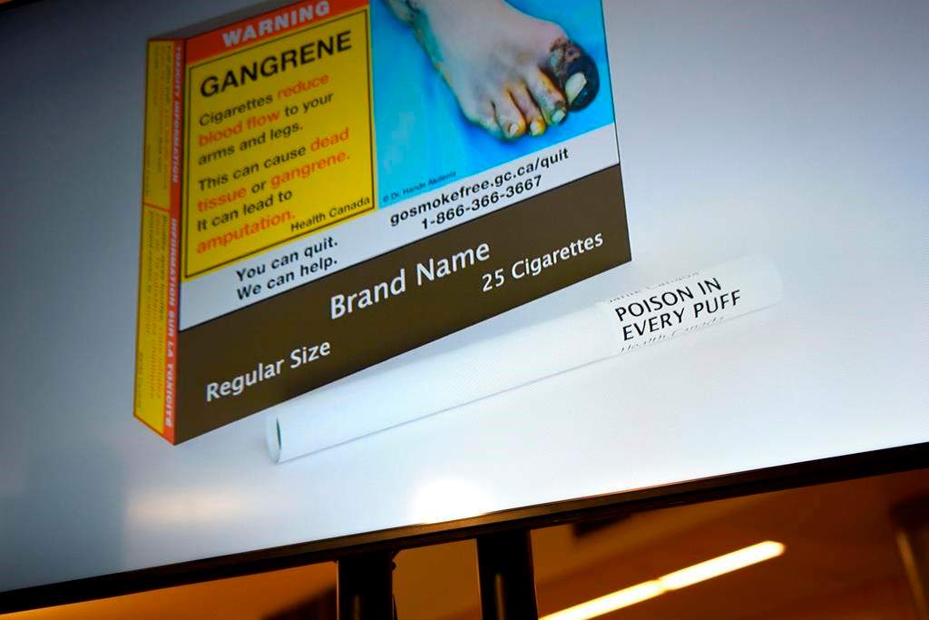 New Health Canada regulations that require warning labels to be printed on individual cigarettes are coming into effect Tuesday. An example of cigarette packaging with expanded warnings, including a warning printed on the cigarettes themselves, is shown on a screen after a news conference, in Ottawa, Friday, June 10, 2022.