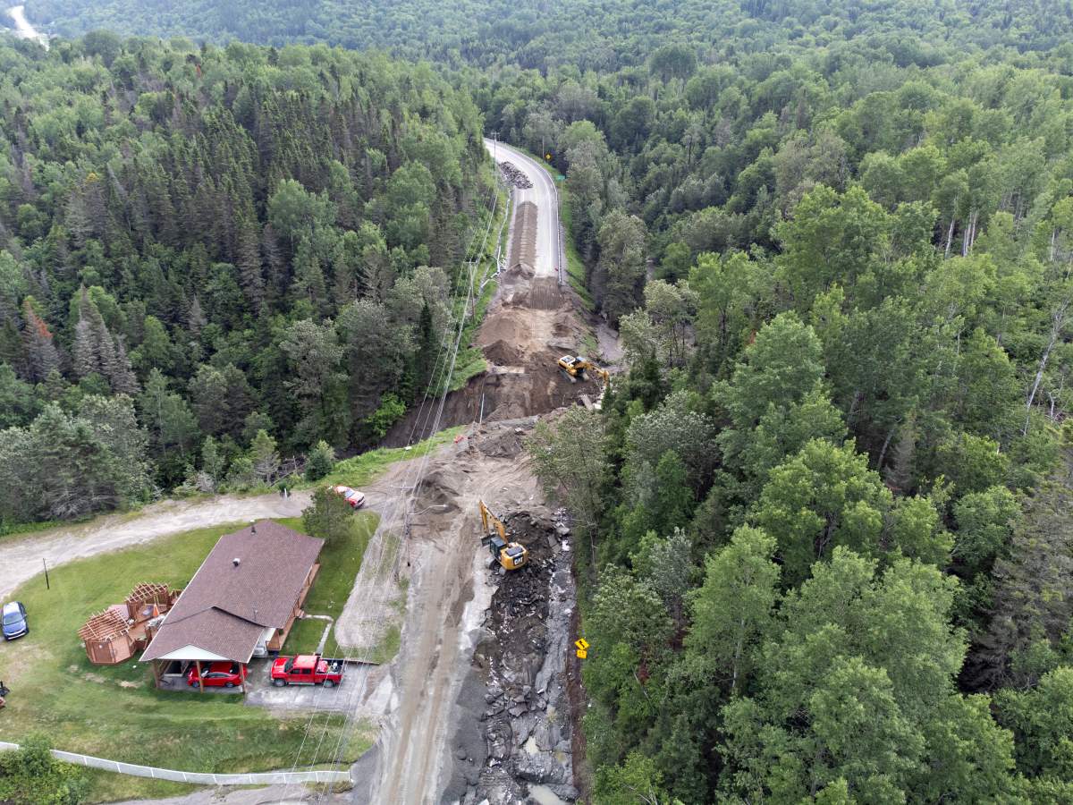 Crews begin repairs to a washed-out section of highway 170 in Riviere-Eternite, Que., Sunday, July 2, 2023. A major landslide caused by heavy rain cut highway 170 between Saguenay, Que., and Saint-Simeon. Two people are missing after they were swept from the road by flood waters.