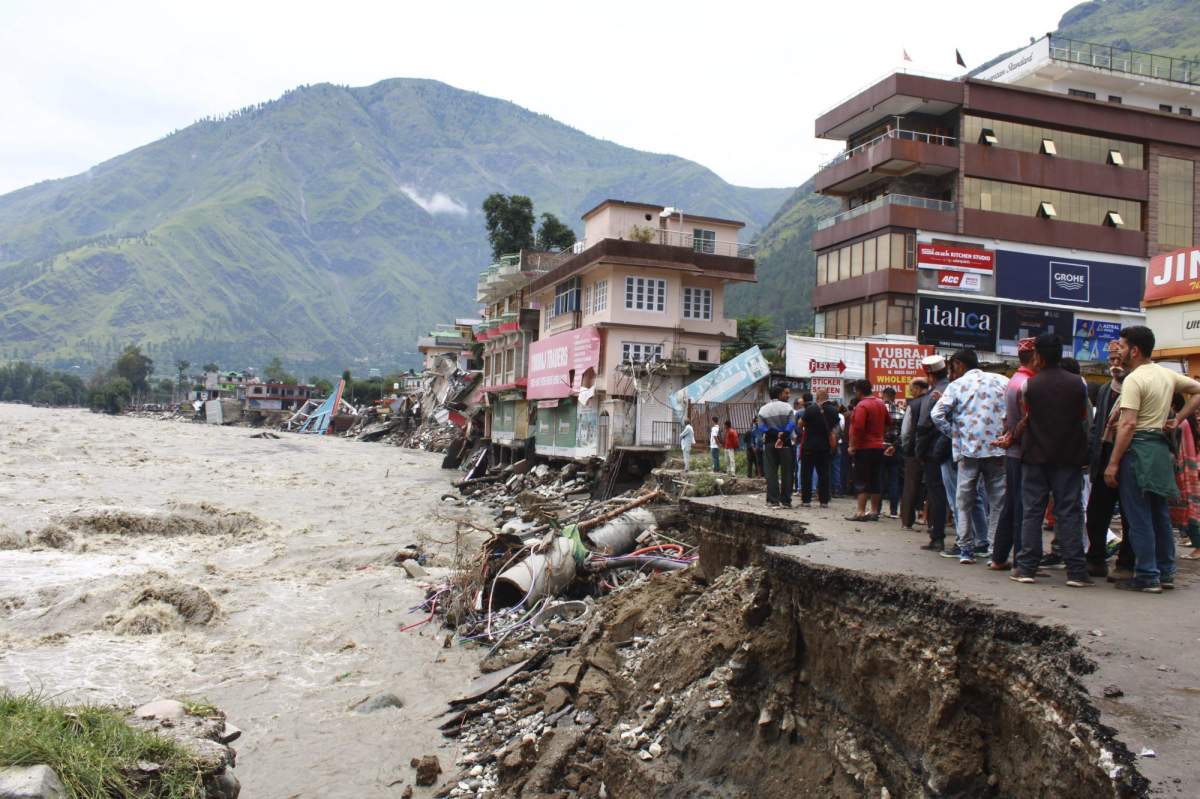 People stand by a road washed away by the River Beas swollen due to heavy rains in Kullu District, Himachal Pradesh, India, Tuesday, July 11, 2023. Heavy monsoon rains caused landslides and flash floods in the country’s north, killing at least 15 people over the past few days. (AP Photo/Aqil Khan)