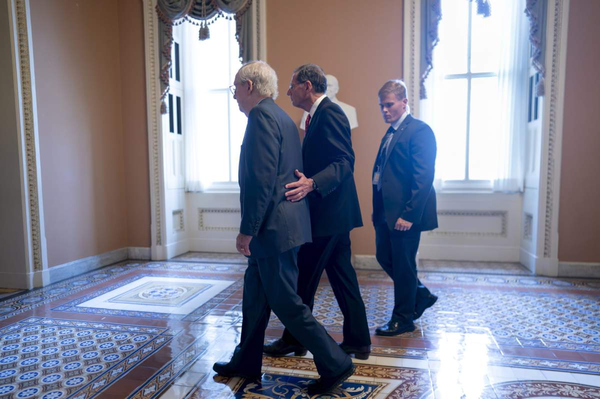 Senate Minority Leader Mitch McConnell, R-Ky., left, is assisted by Sen. John Barrasso, R-Wyo., second from right, and a Capitol Police officer after the 81-year-old GOP leader froze at the microphones as he arrived for a news conference at the Capitol in Washington, Wednesday, July 26, 2023. McConnell went to his office for a few minutes and returned to speak with reporters. (AP Photo/J. Scott Applewhite)