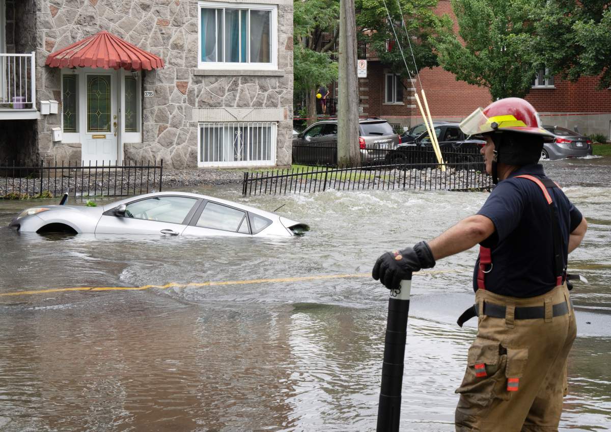 A firefighter surveys the scene after a water main broke flooding several blocks Friday, July 28, 2023 in Montreal.