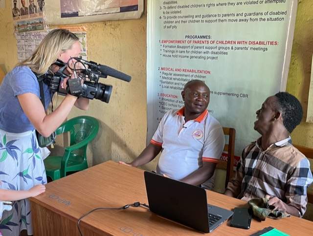 Wilbert, an 18-year-old Ugandan with cerebral palsy pictured next to his father, has been hired by a Canadian organization to develop educational software for children with visual or hearing impairments.