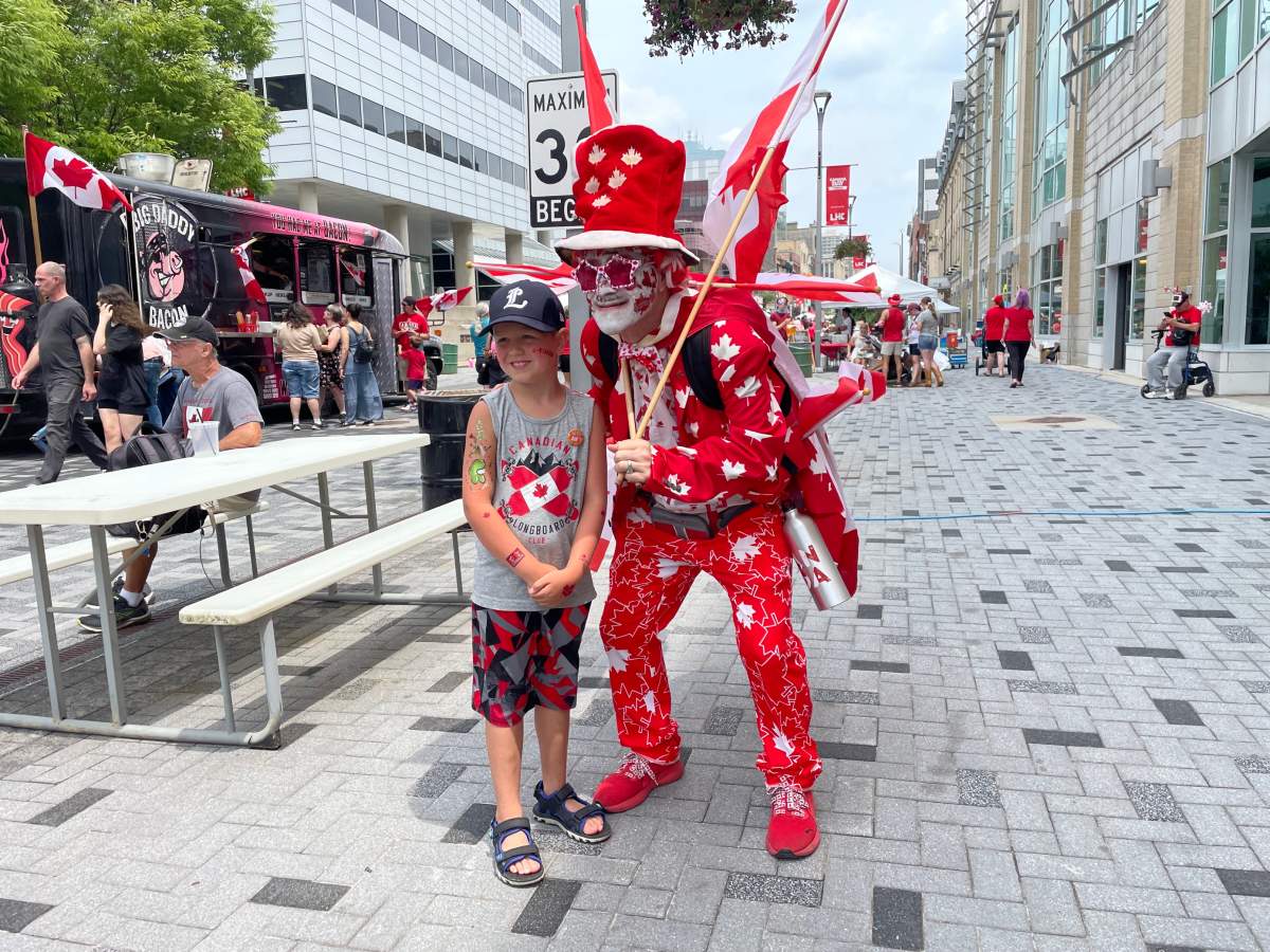 Jaxson Lelacheur, left, takes a picture with Greg Sturm along Dundas Place on July 1, 2023.