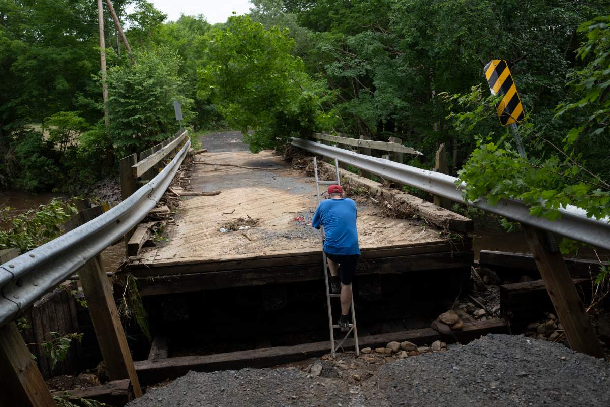 A man surveils damage to a bridge hit by floods.