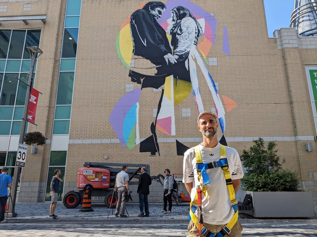 Artist Kevin Ledo stands in front of the mural depicting Johnny Cash and June Carter he painted.