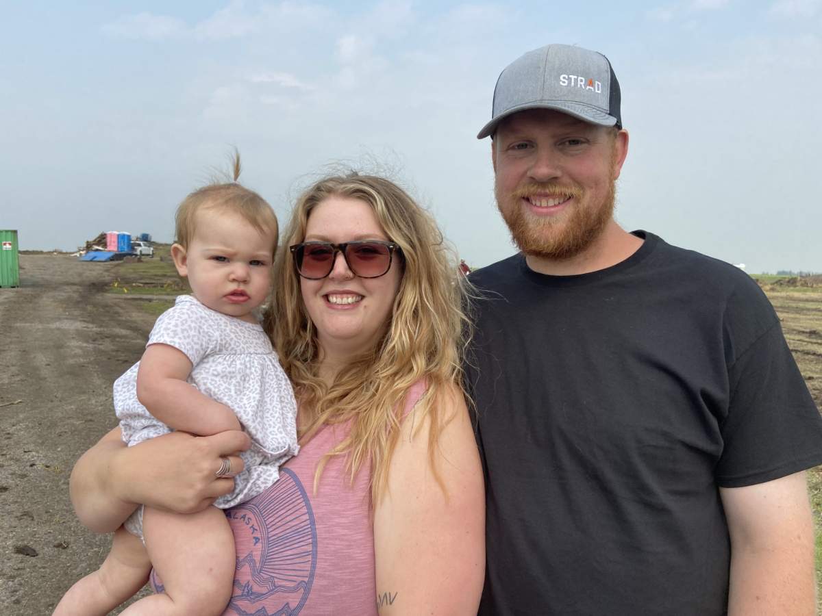 Rosalie, Kari and Travis Kellsey stand in front of where their home used to be in Carstairs, Alta.