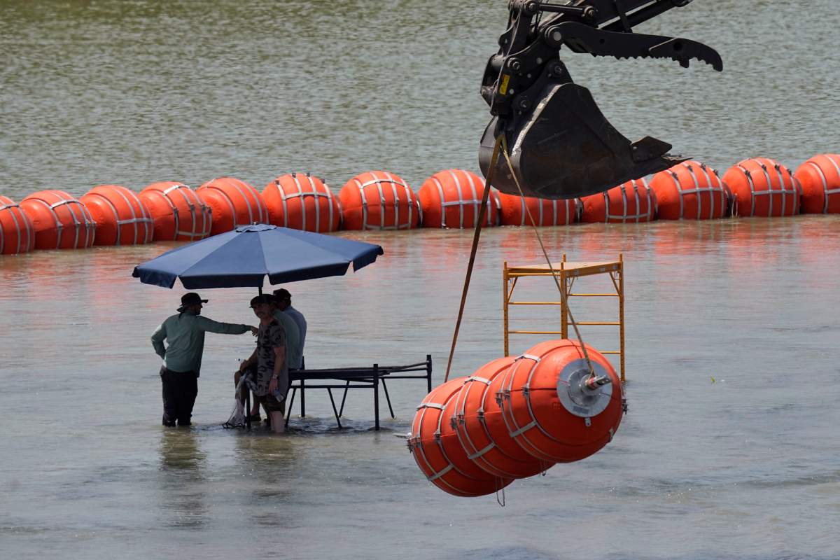 Workers take a break from deploying large buoys to be used as a border barrier along the banks of the Rio Grande in Eagle Pass, Texas, Wednesday, July 12, 2023. The floating barrier is being deployed in an effort to block migrants from entering Texas from Mexico. (AP Photo/Eric Gay)