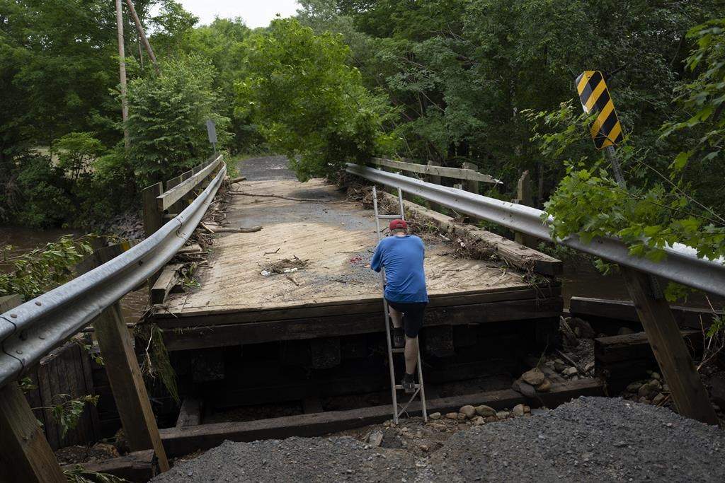Ron Crawford climbs up a ladder onto a washed-out bridge after checking on stranded neighbours near McKay Section, N.S. on Sunday, July 23, 2023. Volunteer firefighters say an alert warning citizens not to leave their homes during July 22 flooding in a rural Nova Scotia county took close to two hours to send, and the process needs to be reviewed. THE CANADIAN PRESS/Darren Calabrese