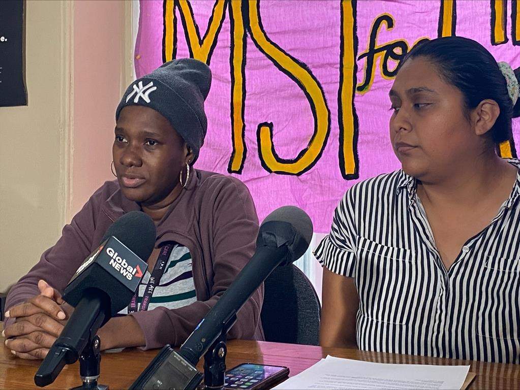 Kerian Burnett, left, and Stacey Gomez, right, speak to reporters in Halifax on Monday, Aug. 14, 2023. Burnett arrived in Nova Scotia from Jamaica to work on a strawberry farm, but says she was fired after her cancer diagnosis, leaving her without medical coverage.