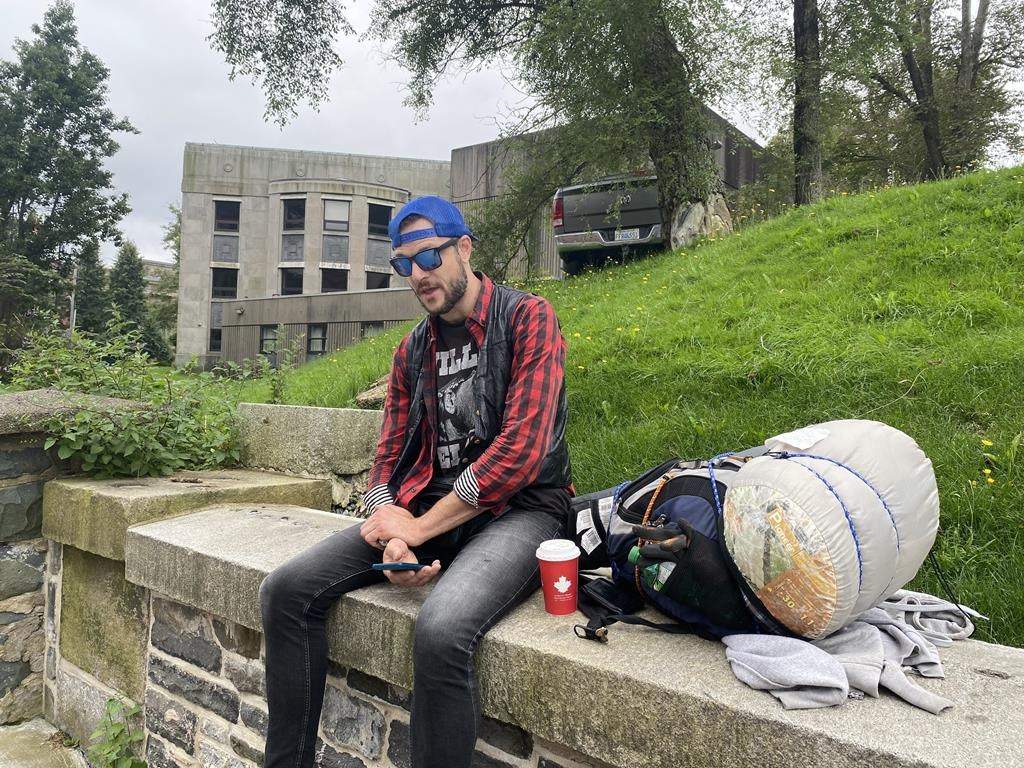 Scott Hutchins sits on a low ledge in downtown Halifax with his backpack, sleeping bag and tent in Wednesday Aug. 16, 2023. He recalls the scene he saw two years ago, when a homeless encampment was razed, and a largely peaceful protest took a rough turn.