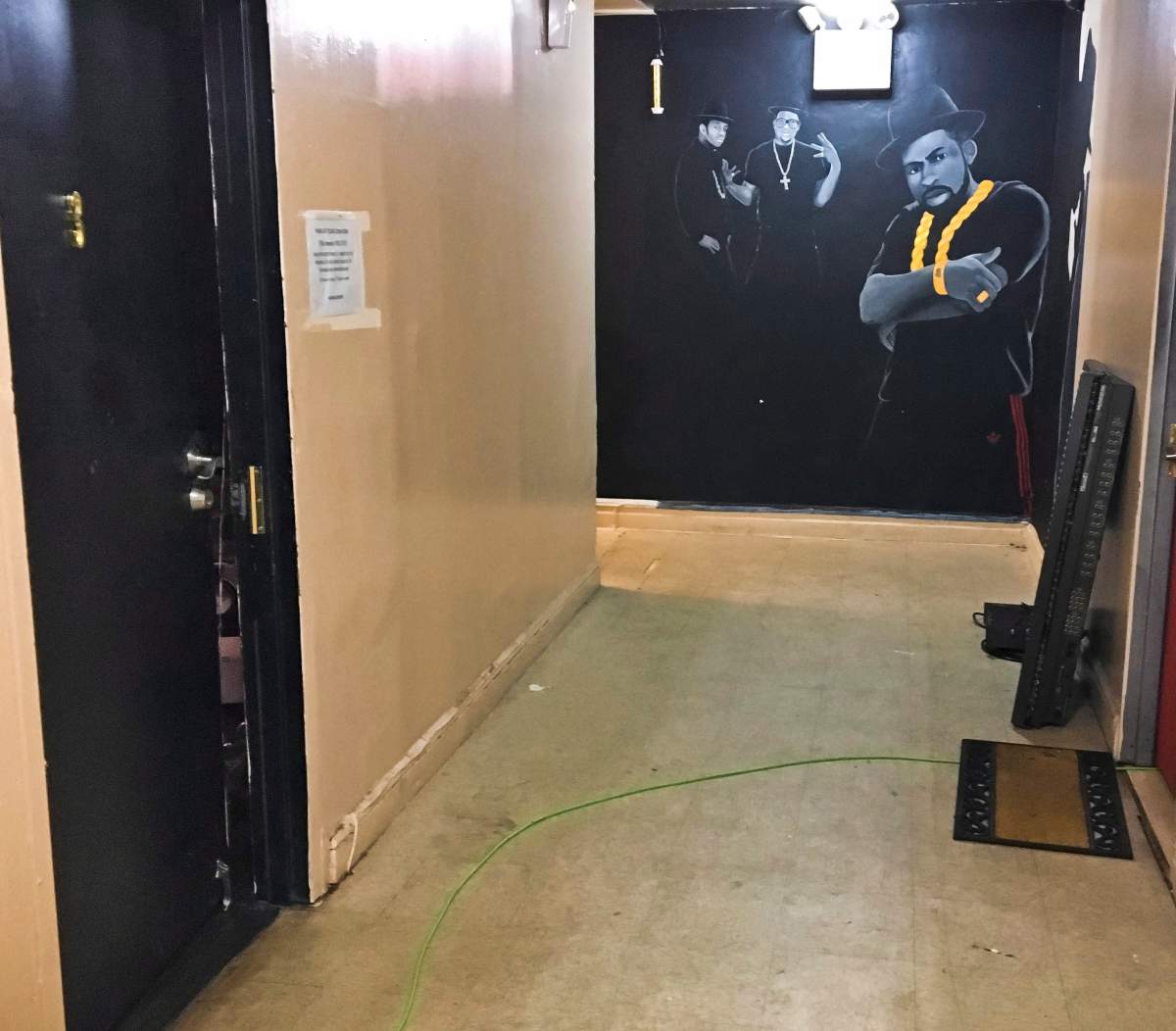 This Thursday Oct. 26, 2017 shows a hallway wall mural of rap group Run-D.M.C., prominently featuring Jason Mizell, right, known as Jam-Master Jay, near the doorway entrance, left, to the room where he was shot. (AP Photo/Tom Hays)