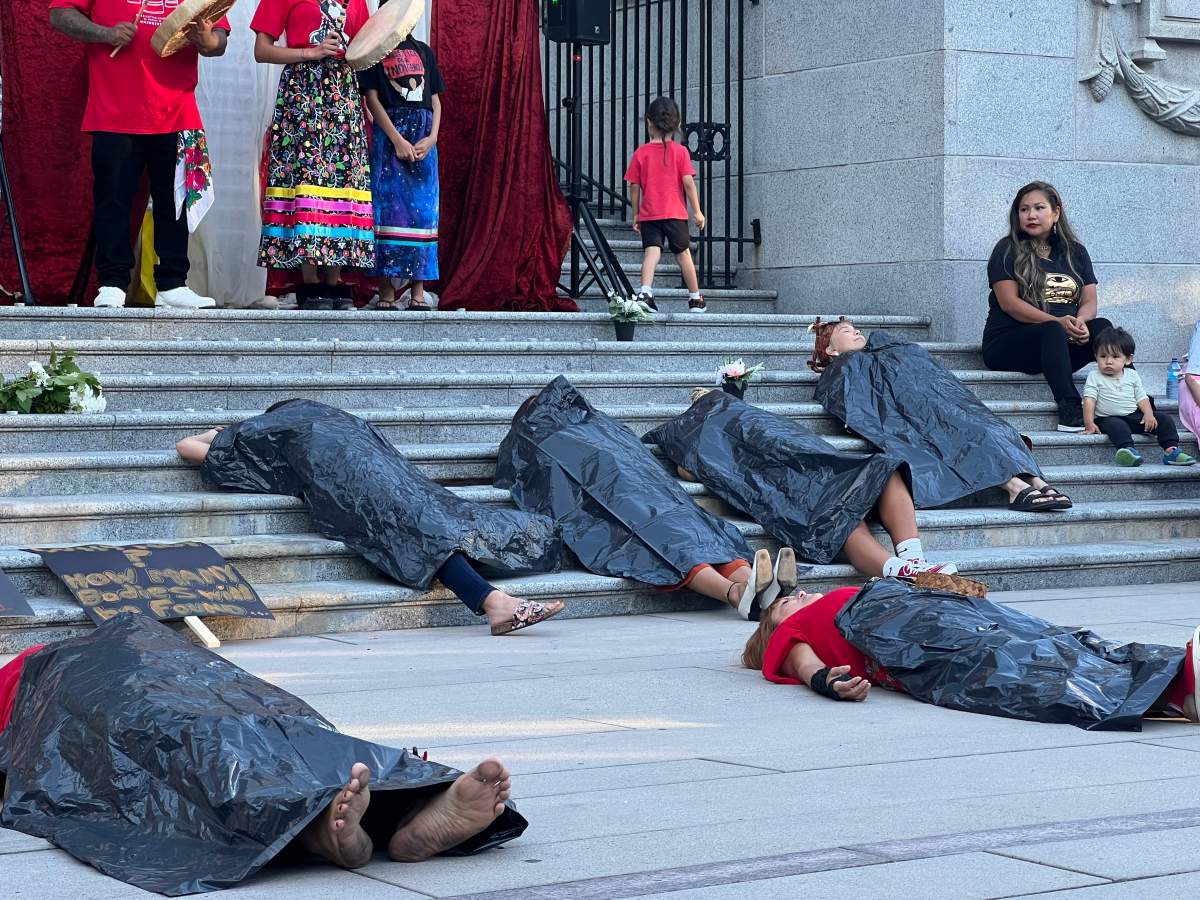 A group of women lay with garbage bags covering themselves.