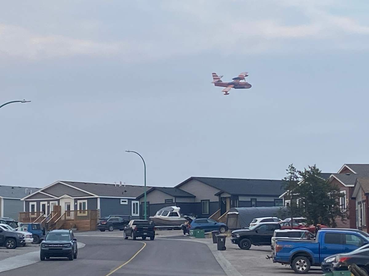 A water bomber flies over a neighbourhood in Yellowknife, Northwest Territories on August 16, 2023.