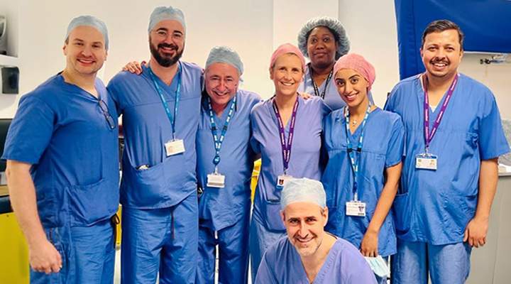 Medical professionals stand in blue scrubs.