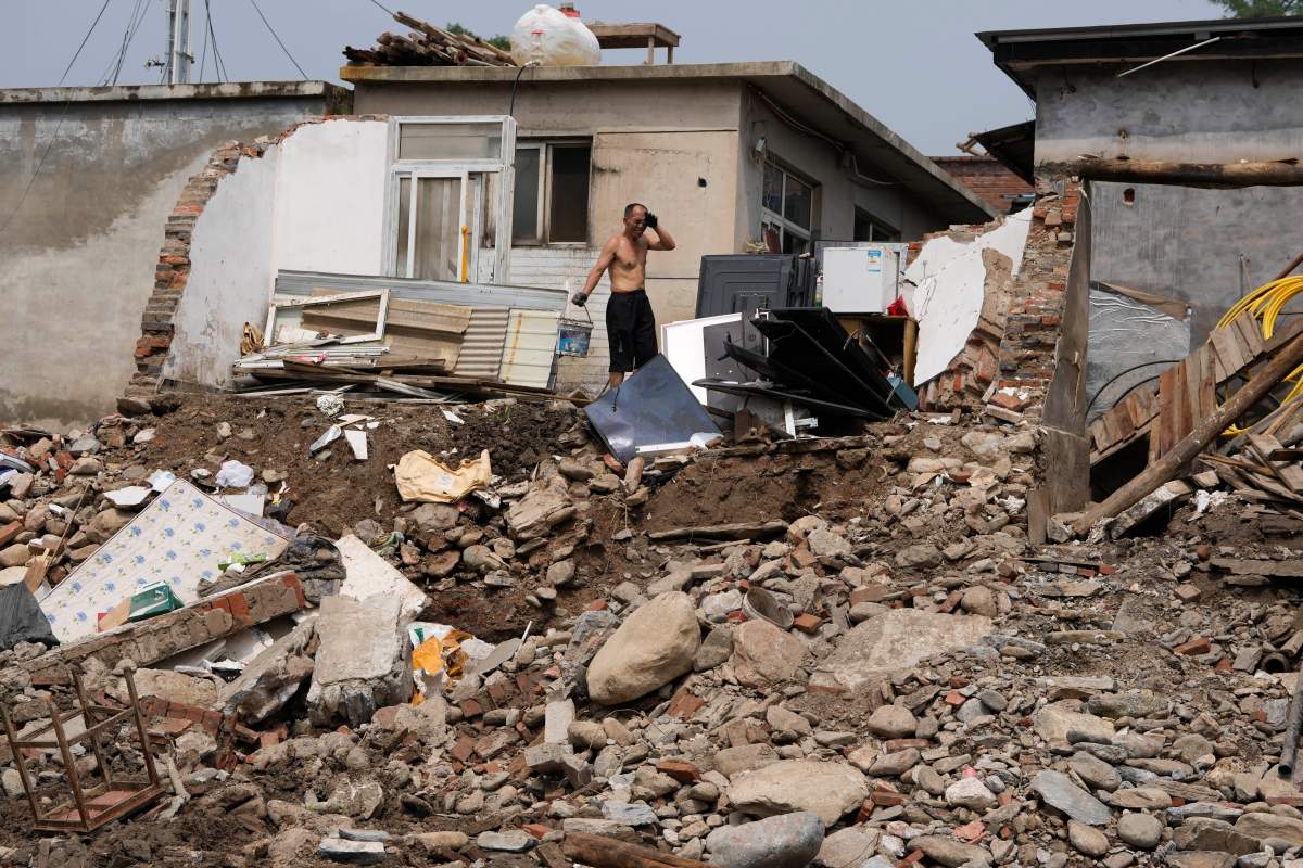 A man reacts as he clears mud from a house in the flood devastated Nanxinfang village on the outskirts of Beijing, Friday, Aug. 4, 2023.