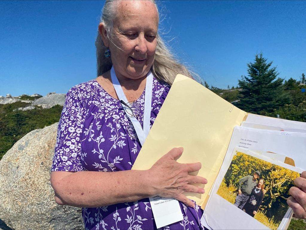 Claire Mortimer poses with a photo of herself and her father, John Mortimer, who died in the Swissair Flight 111 plane crash in Sept. 1998, at the Peggy’s Cove Swissair Memorial in Indian Harbour, N.S. on Sunday, Sept.3, 2023. On the 25th anniversary of the tragedy, her main concern is for the first responders who struggle with post-traumatic stress disorder. THE CANADIAN PRESS/Marlo Glass