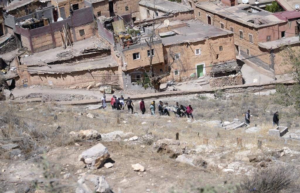 People prepare to burry a man who was killed by the earthquake, in Moulay Brahim village, near Marrakech, Morocco, Saturday, Sept. 9, 2023. (AP Photo/Mosa’ab Elshamy)
