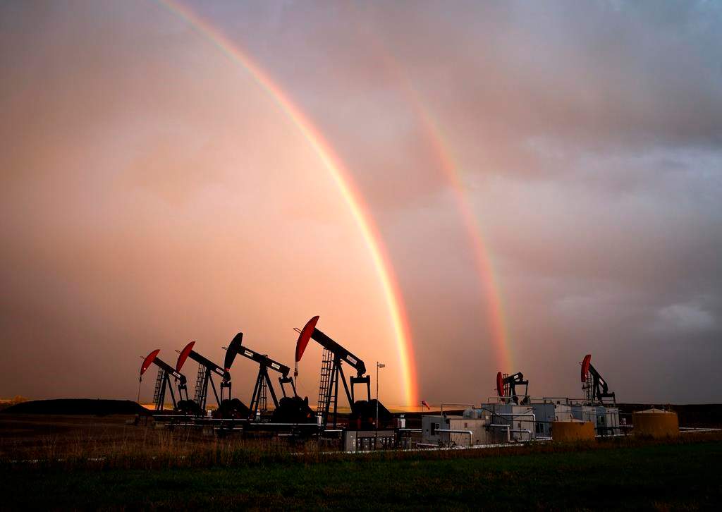 A rainbow appears to come down on pumpjacks drawing out oil and gas from wells near Calgary, Alta., Monday, Sept. 18, 2023.