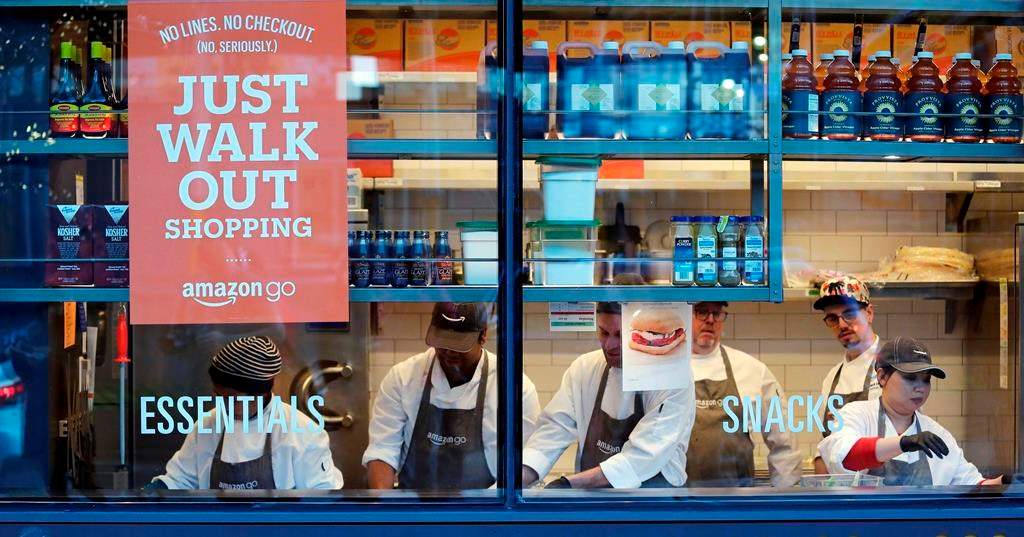 In this Jan. 22, 2018, file photo, workers as seen from a sidewalk window as they assemble sandwiches in an Amazon Go store in Seattle. Toronto and Calgary sports fans will soon be able to skip the lineup when purchasing snacks before or during games. 