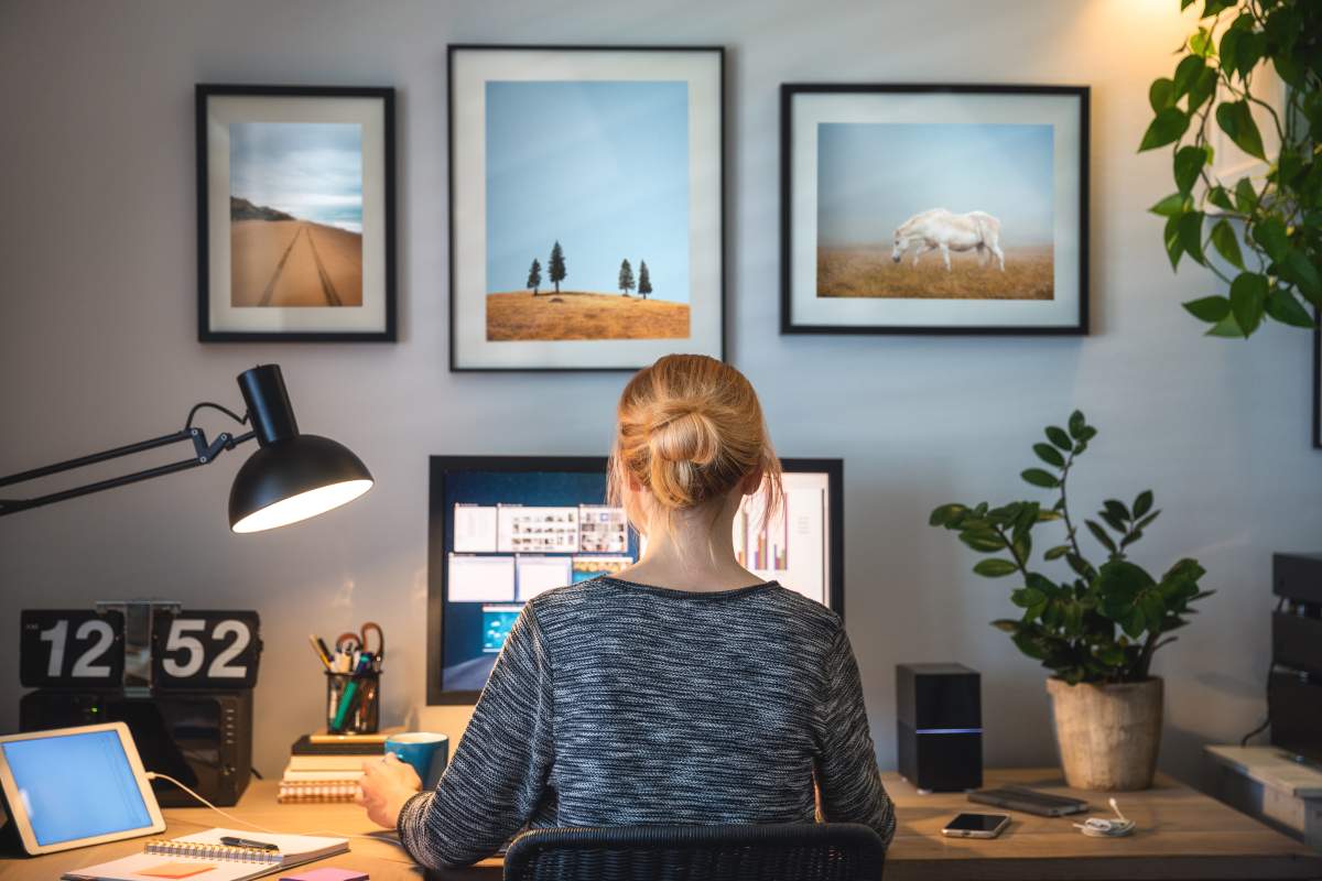 woman with a grey sweater and a bun sitting at a desk at her house working on the computer