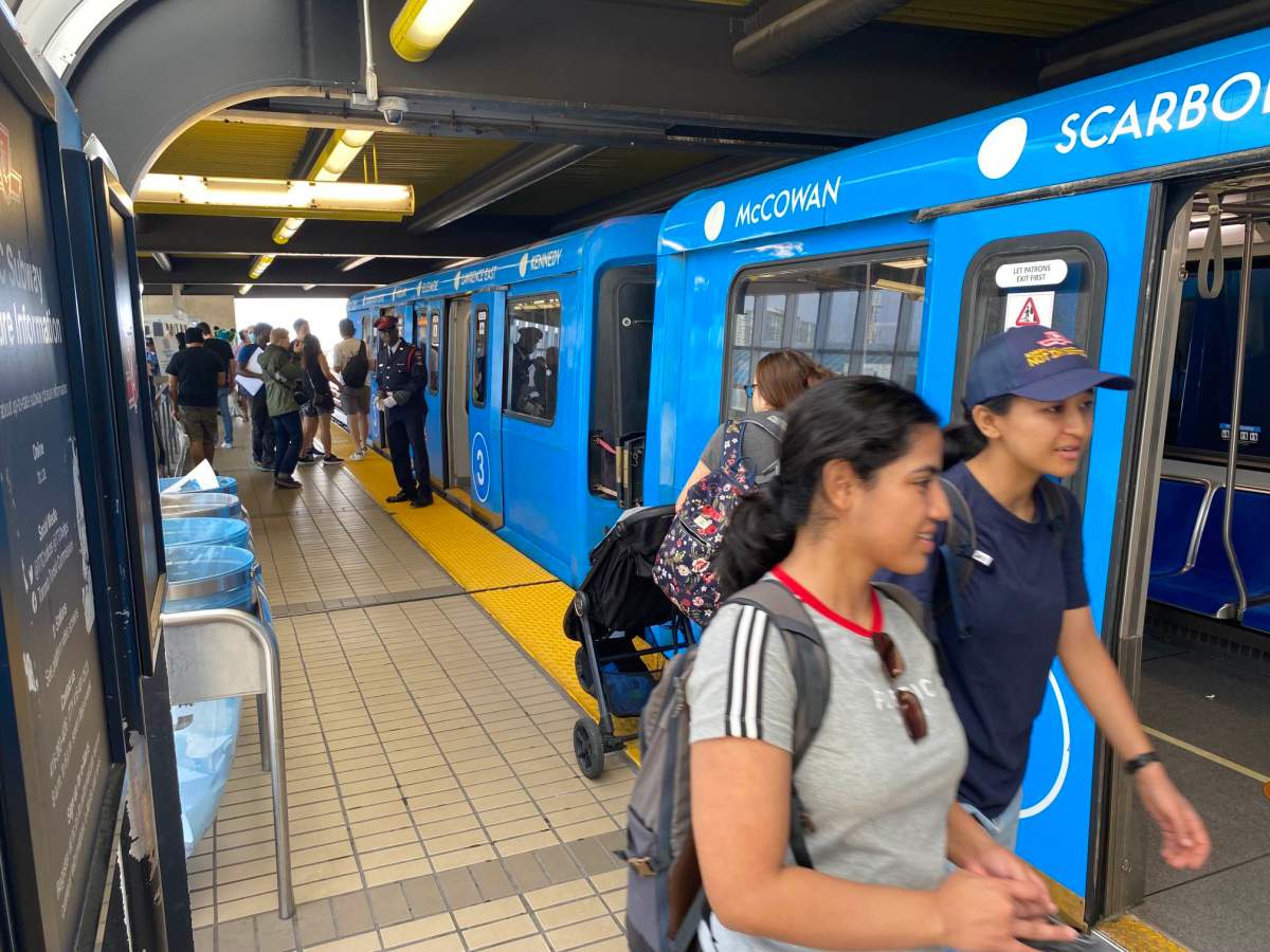 People standing by a blue subway train.