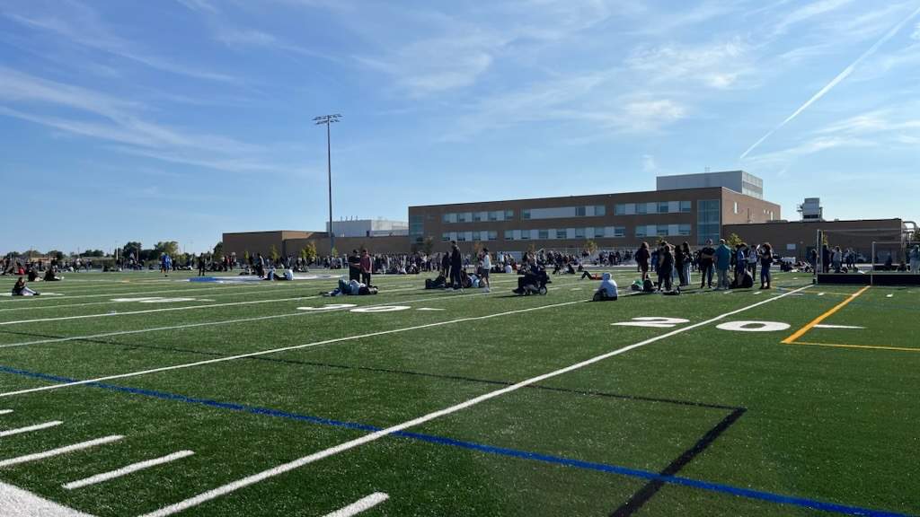 Students from Nora Frances Secondary School congregated on a football field at the facility following an evacuation amid a threat on Sept. 22, 2023.
