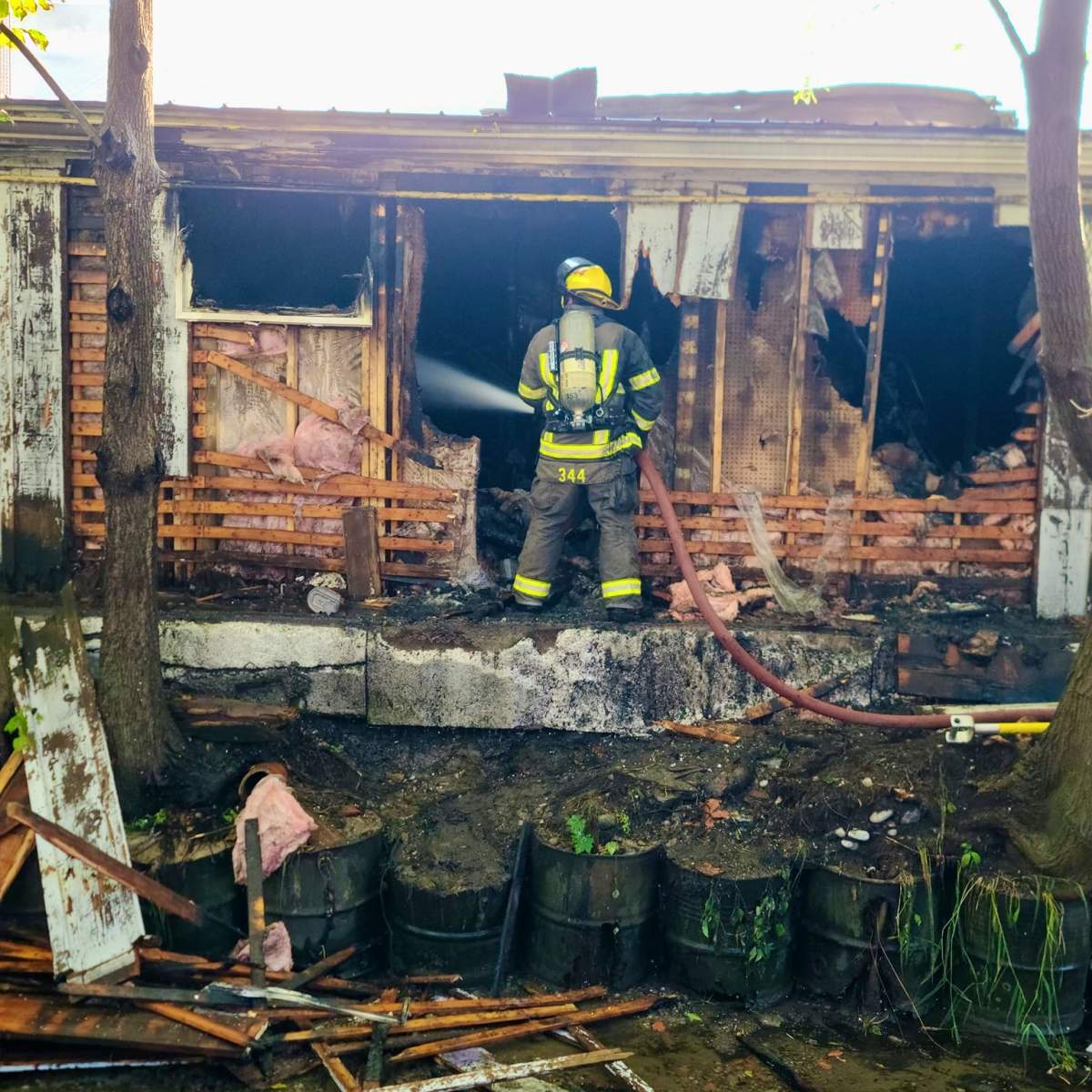 A firefighter douses hot spots following a fire at the Beyond the Blue Box thrift store in Cobourg on Sept. 20, 2023. The fire is no longer considered suspicious.