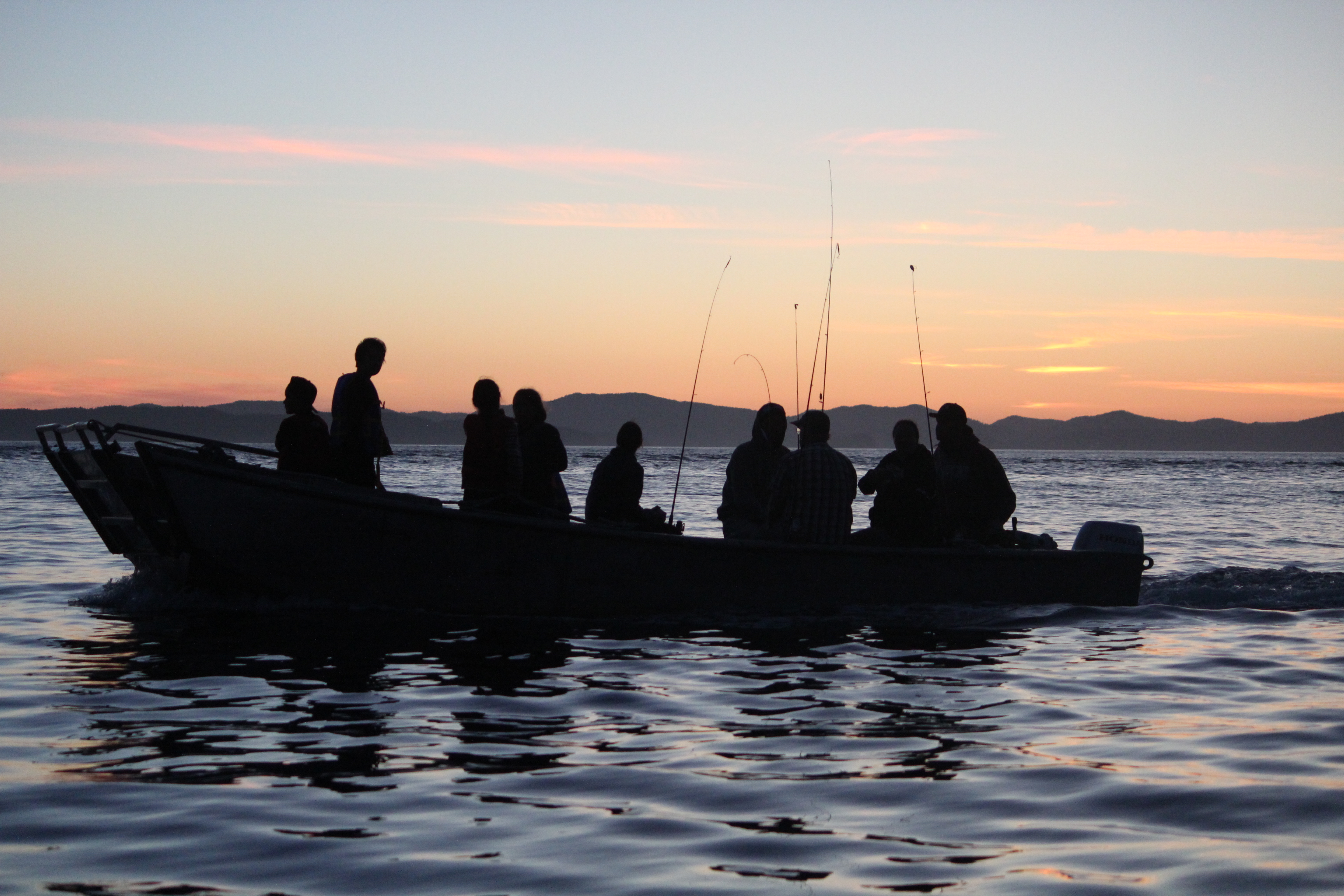 A sunset image of people in a canoe fishing