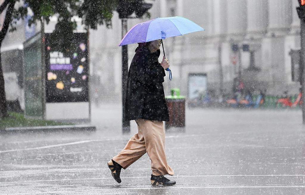 A person walks along a street during heavy rain in Montreal, Saturday, October 7, 2023. Environment Canada has issued a rainfall warning for the province.