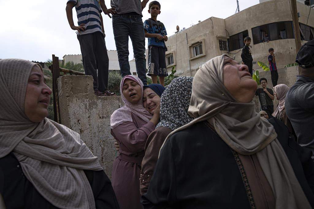 Relatives mourn people killed in an Israeli air strike in Gaza City on Monday. Israel’s military battled to drive Hamas fighters out of southern towns and seal its borders Monday as it pounded the Gaza Strip. (AP Photo/Fatima Shbair)