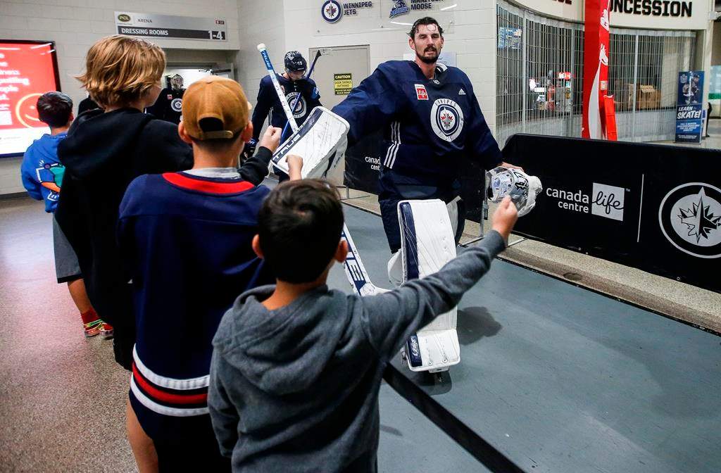 Winnipeg Jets goaltender Connor Hellebuyck (37) high-fives hockey fans as the team changes rinks during day two of their NHL training camp in Winnipeg Sept. 22, 2023. Connor Hellebuyck and Mark Scheifele hope their new contracts show their teammates and fans how much they believe in the Winnipeg Jets.