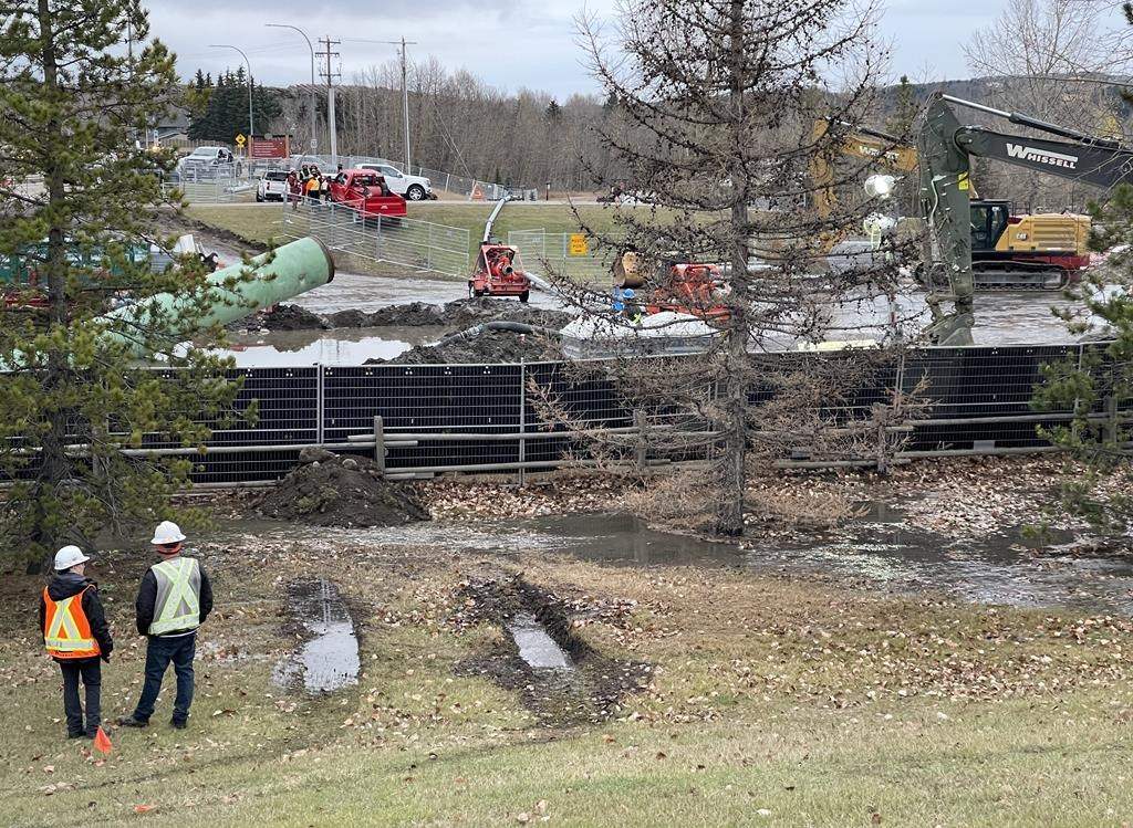 Work crews are shown at a main sewer line break in Cochrane, Alta. on Sunday Oct. 22, 2023.