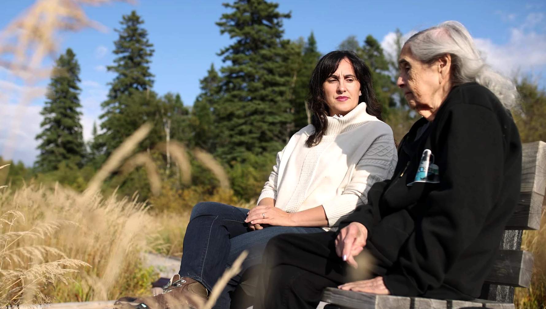 Sitting on a bench along the boardwalk off the Birch Island trail in Happy Valley-Goose Bay, Labrador, Ashlee Cunsolo (left) speaks with Elder Jean Crane (right).