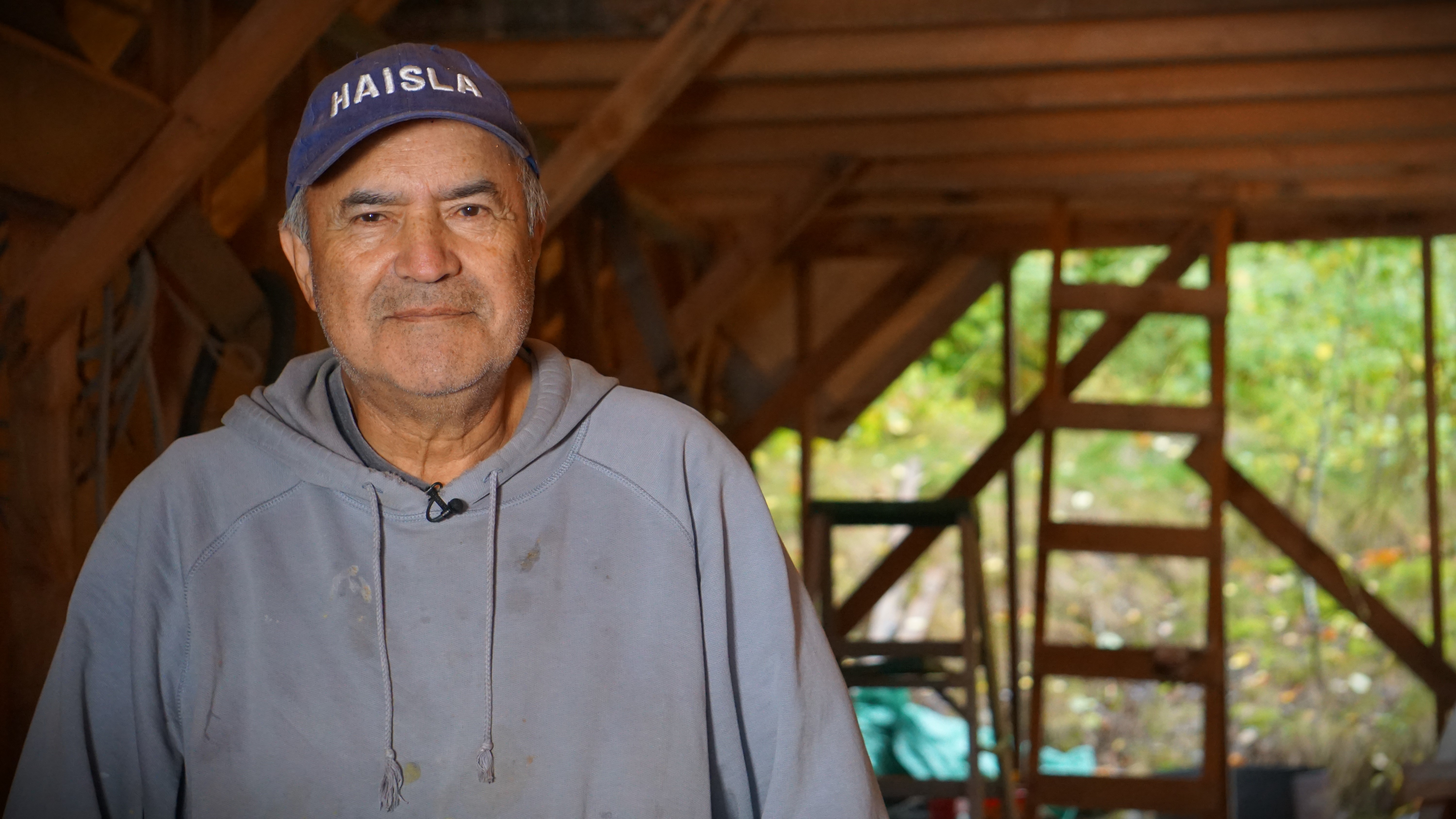 Haisla carver Mike Robinson stands in his tent next to the cedar canoe he's building. Upon its completion, Robinson believes it will be the first oceangoing canoe made in the Haisla Nation in three decades.