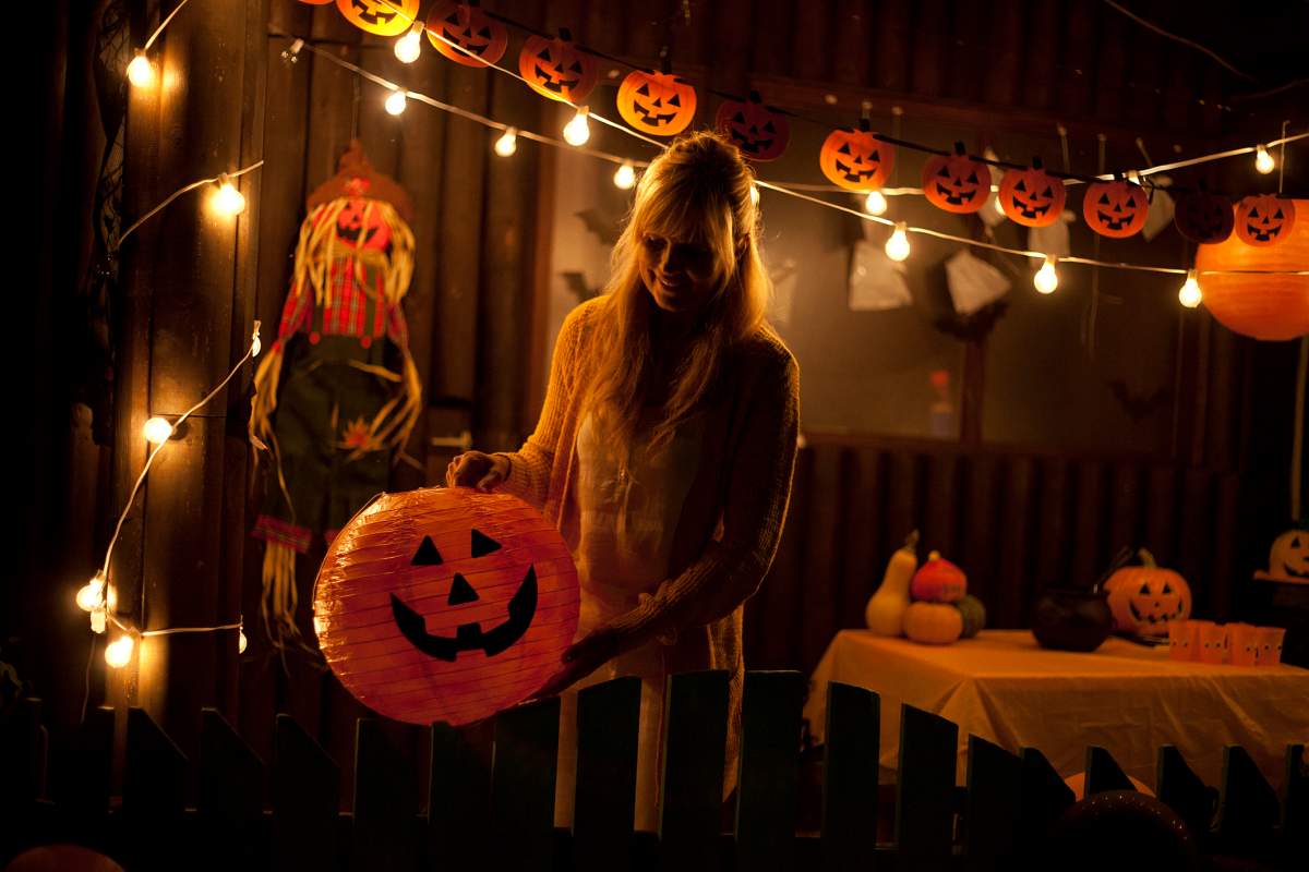 mom decorates for halloween outside with pumpkins and lights