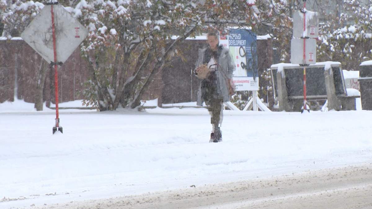 A pedestrian walks along a snowy sidewalk in Calgary on Oct 24, 2023.