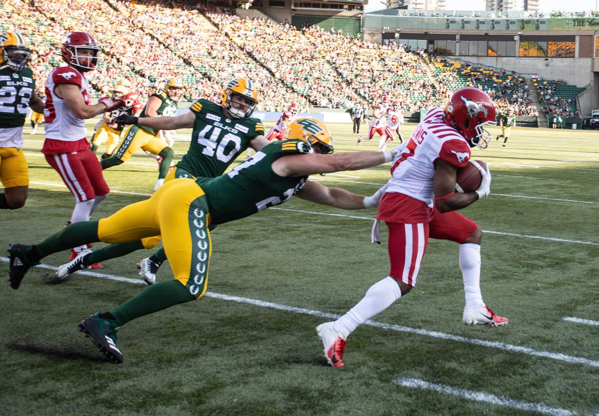 Elks fullback Tanner Green lunges to tackle Stampeders kick-returner Tommylee Lewis.