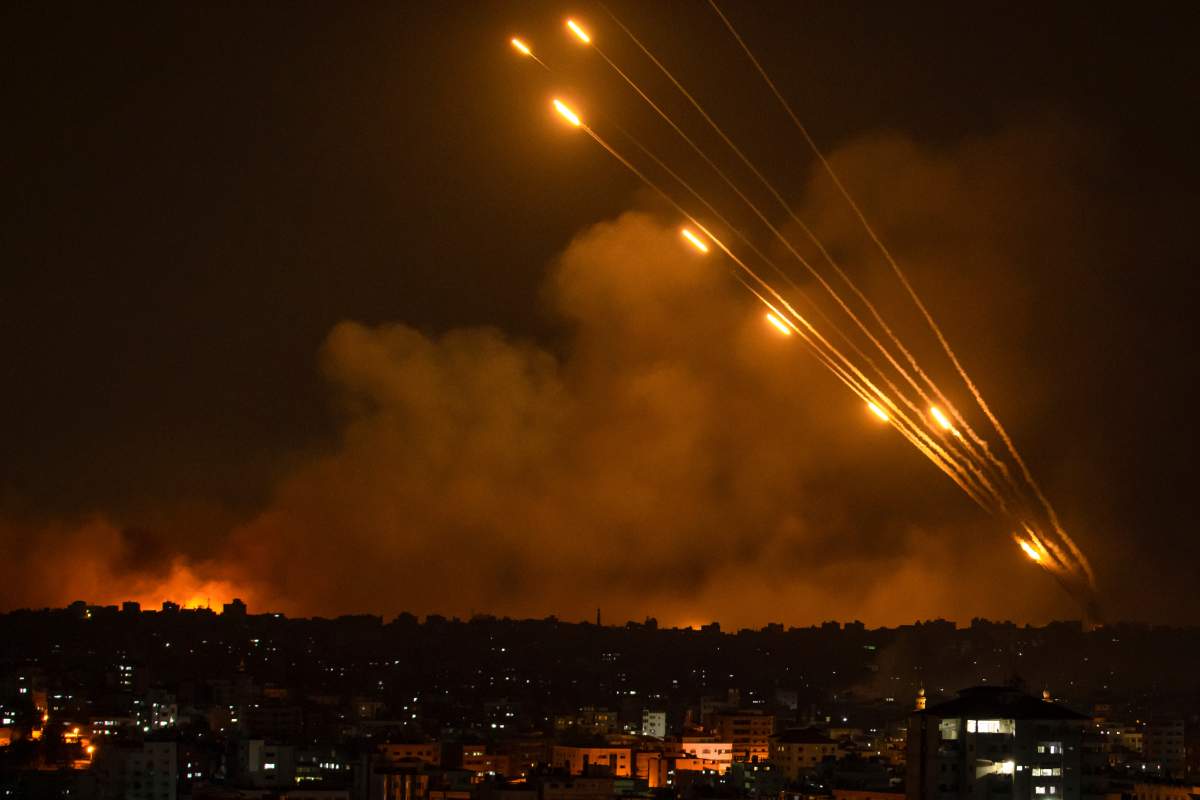Rockets fly and illuminate a smoky, black sky.